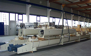 Lange, waagerecht montierte Trogschnecken aus hellem Metall, mit mehreren Antrieben und Aufhängungen, aufgebaut in einer großen Werkhalle.